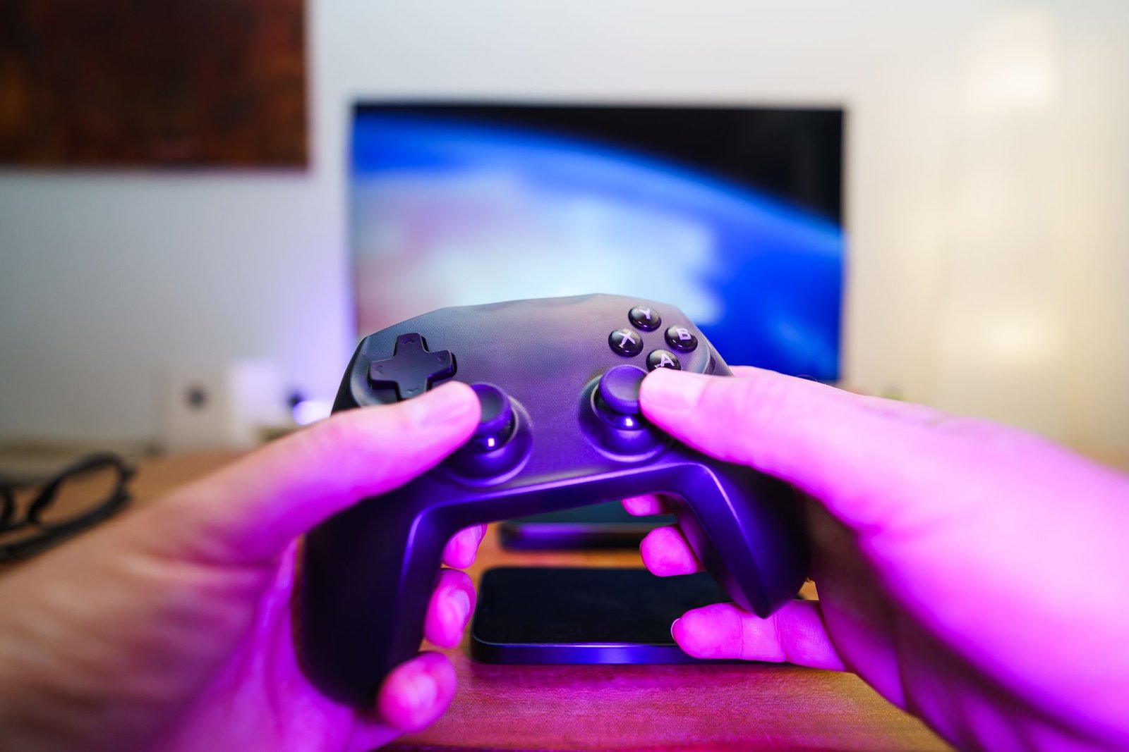 Close-up of hands holding a game controller in front of a TV screen. Perfect for entertainment setups. — Access Your Favorite