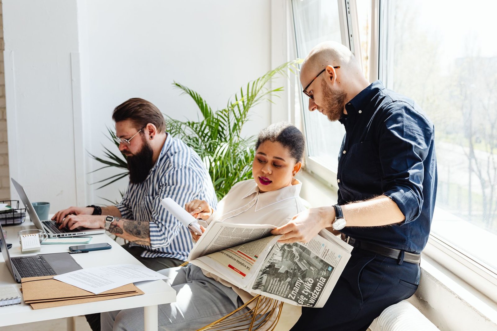 Three colleagues collaborating in a bright office, reading and working on laptops. — Best Non-GamStop Casino Sites UK  Casino