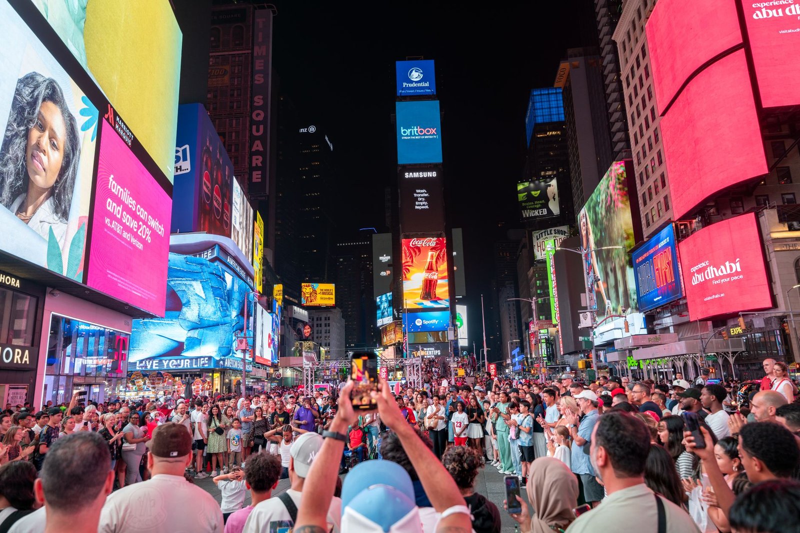 Crowds gather under bright billboards at Times Square, New York, capturing the vibrant city life. — Coronavirus disease 2019