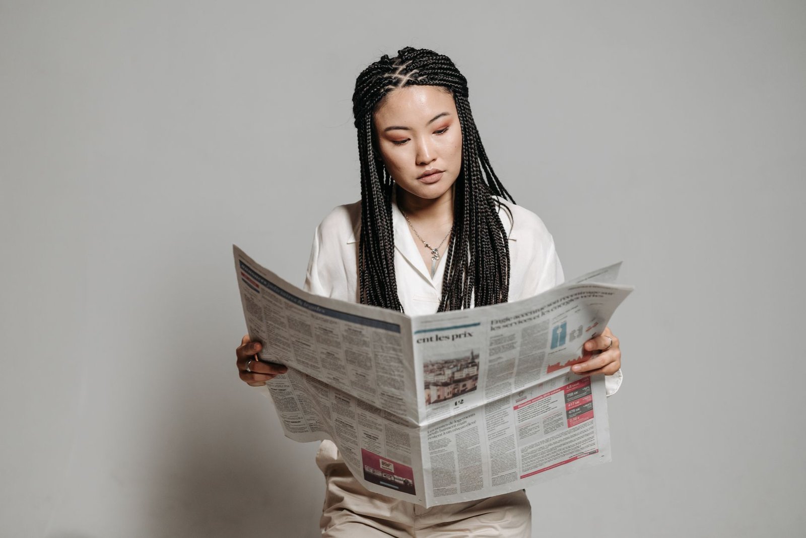 Woman with braided hairstyle reading a newspaper indoors, showing leisure and focus. — Test post title